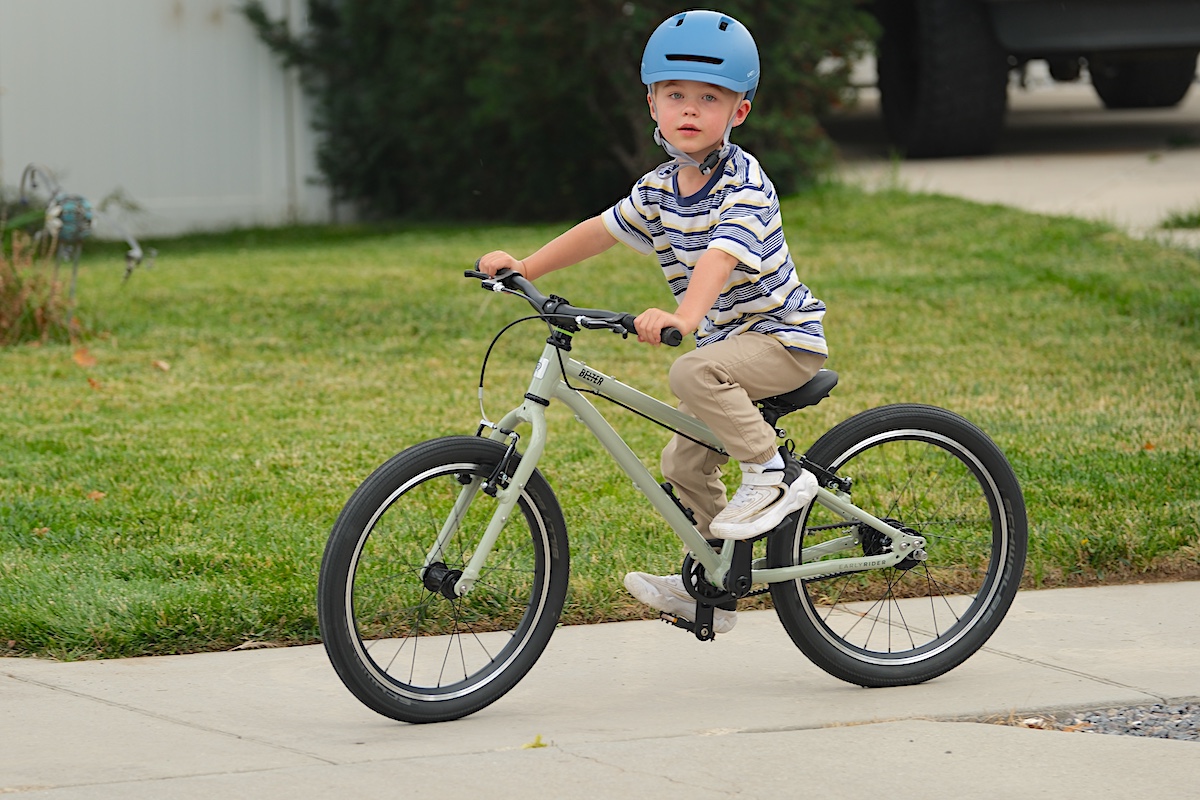young rider riding a green early rider belter 20 inch auto shift bike