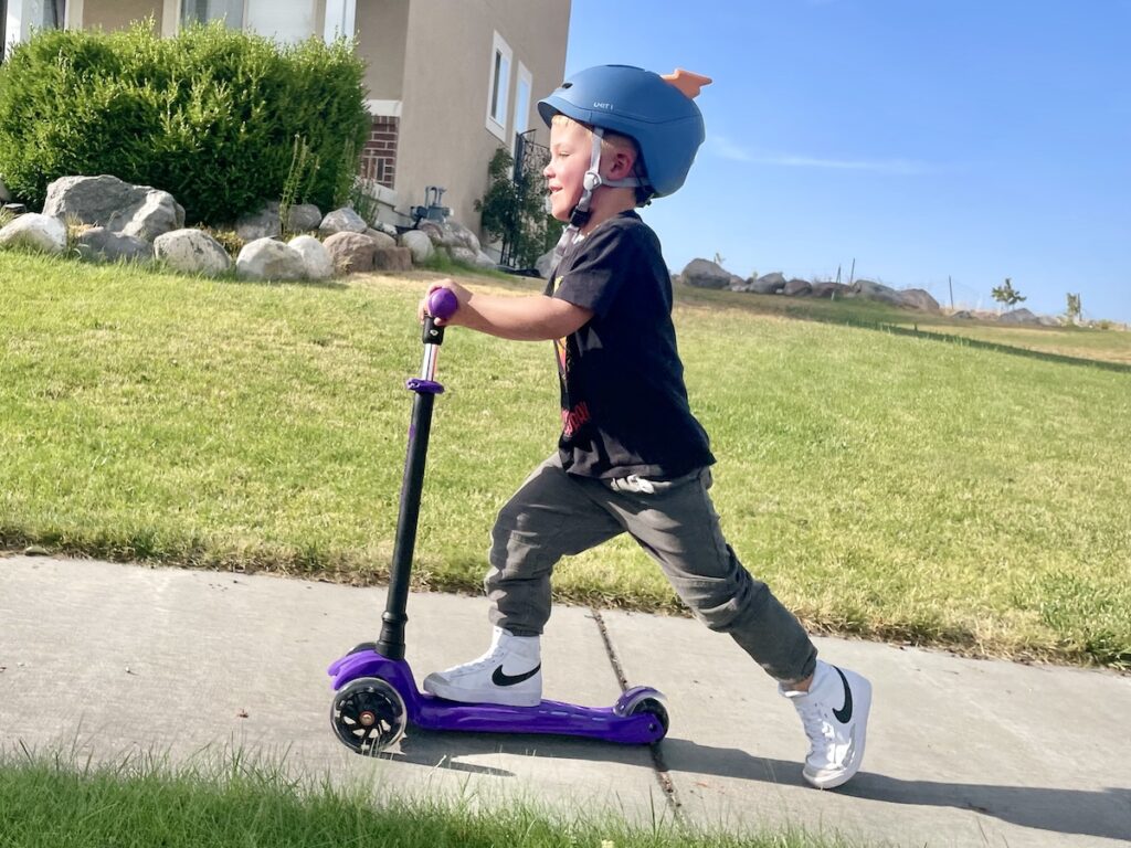 boy riding a scooter wearing the sparky unit 1 helmet