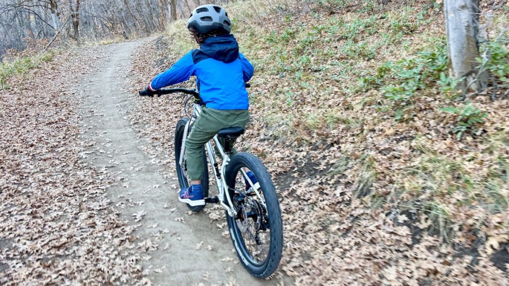 child riding the early rider seeker 24 on a single track trail