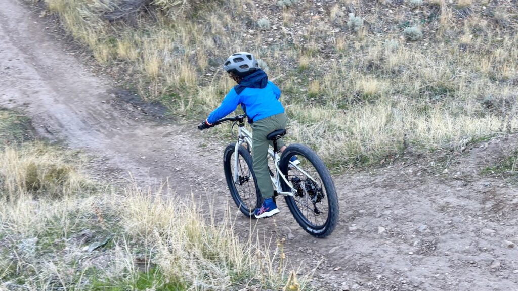 child riding an early rider seeker 24 down a single track trail