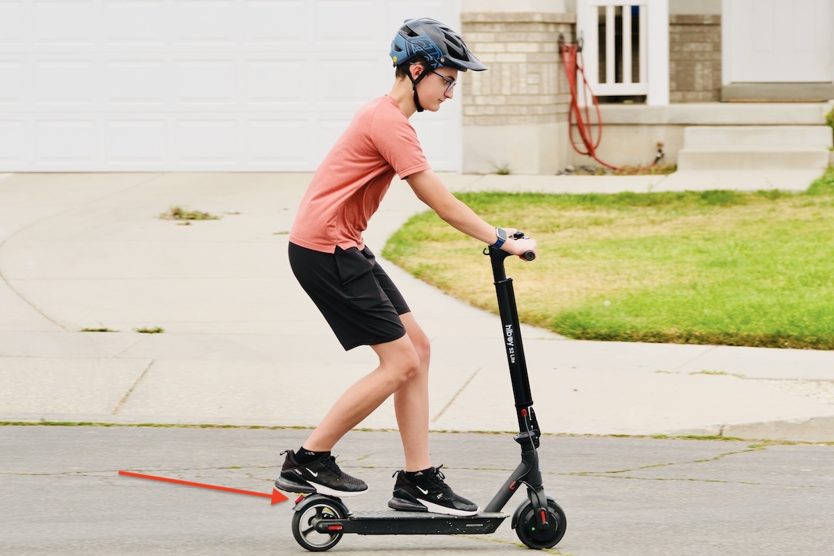 child using a foot brake on an electric scooter